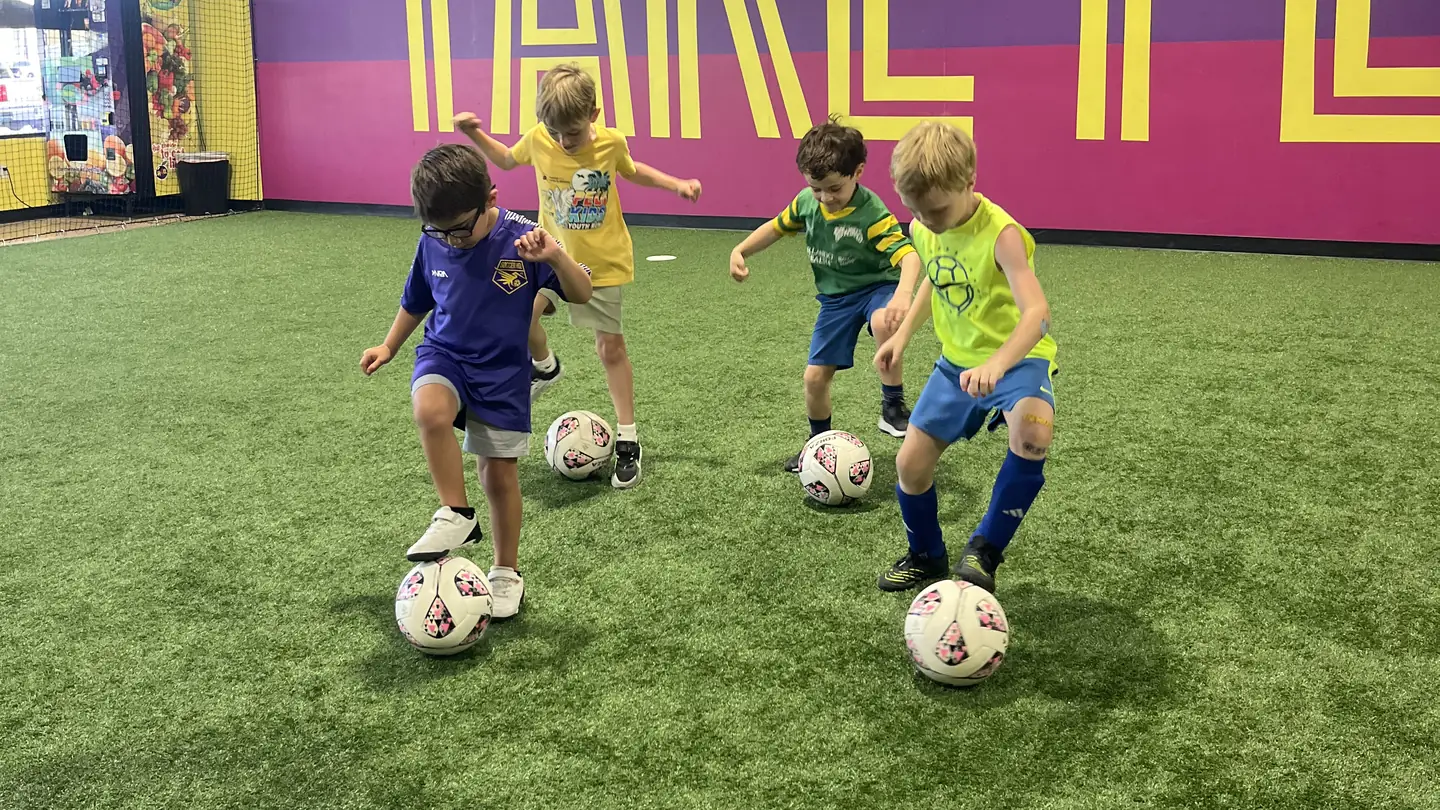 A small group of children playing a small-sided soccer game on Soccer HQ's indoor turf