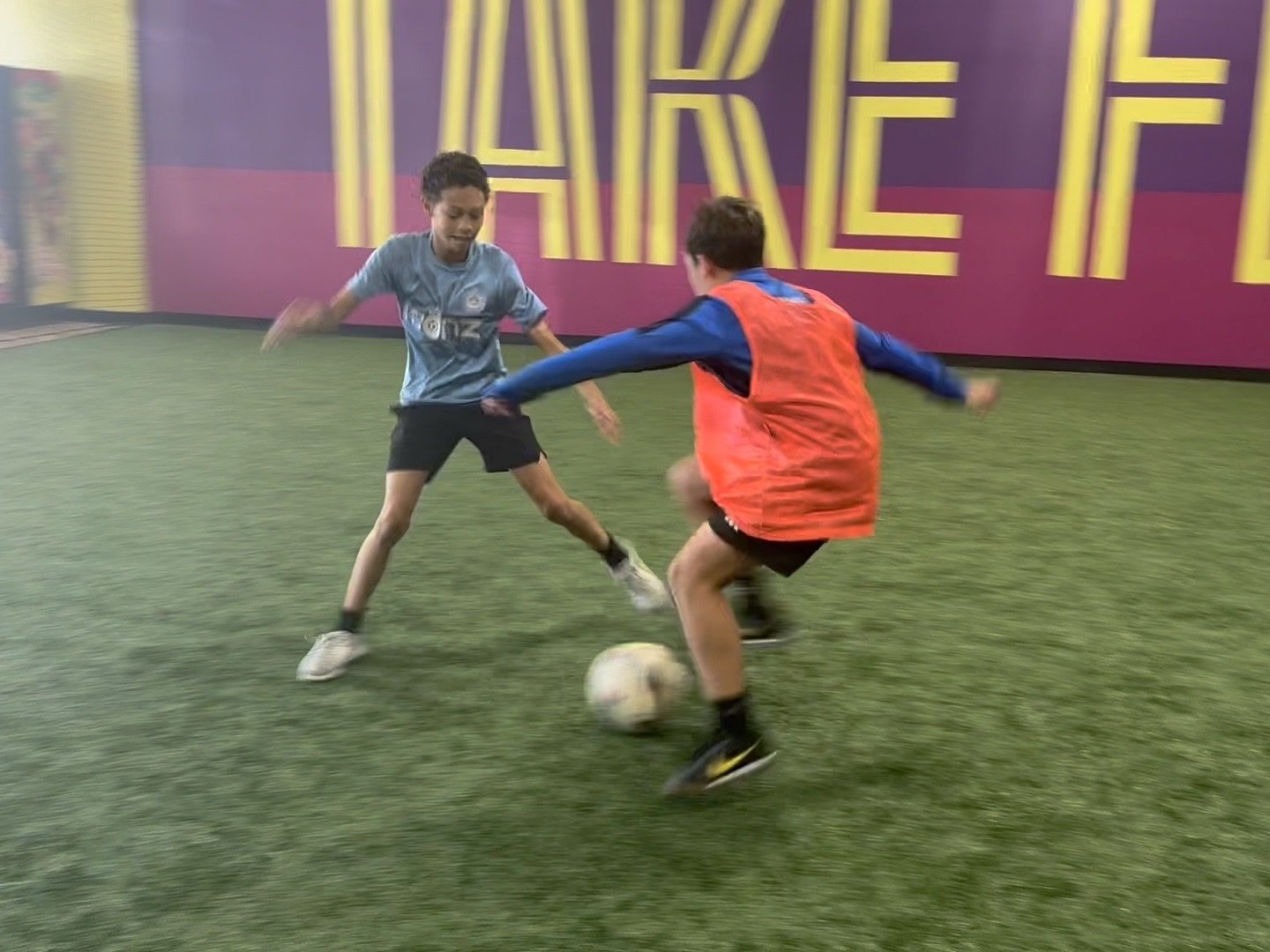 Two players battling for the ball on the indoor turf at Soccer HQ