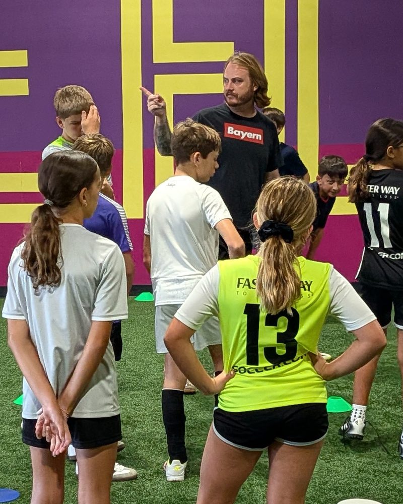 Coach Brandon Klase giving instruction to a small group of players at Soccer HQ